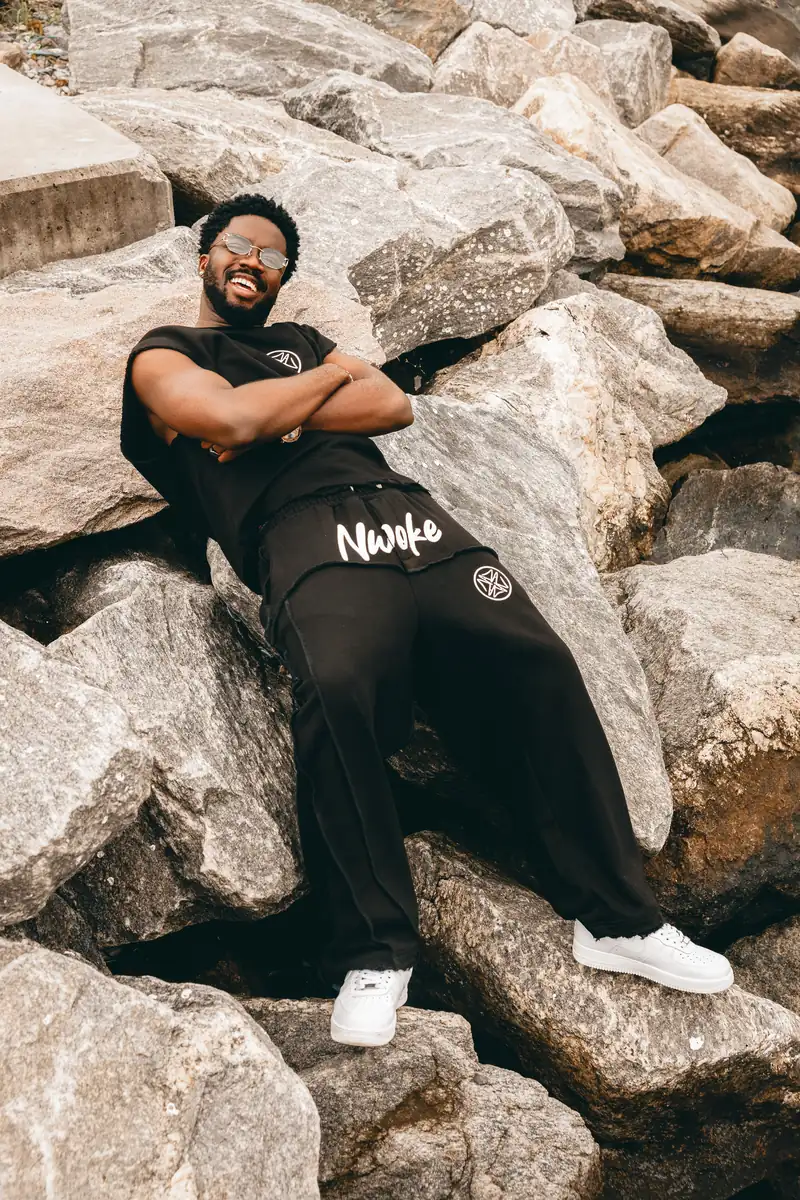 A man in the Black set reclining on the rocks by the water