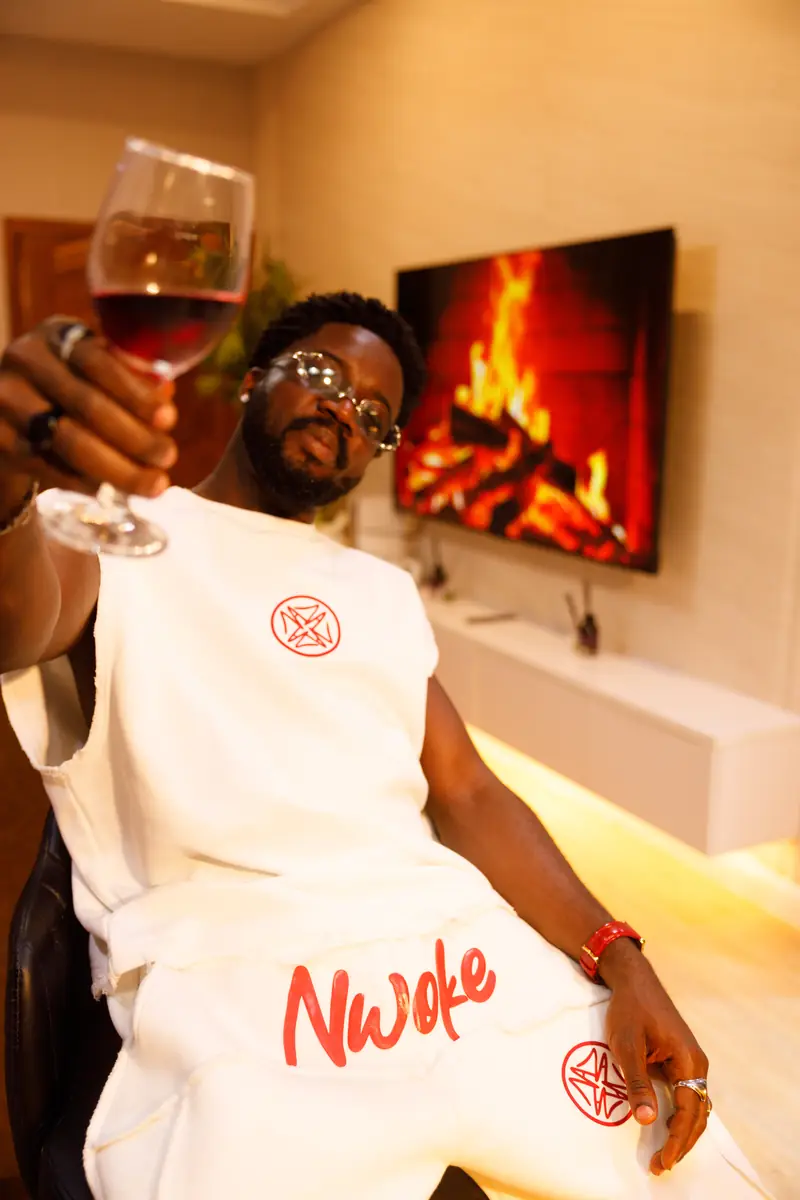A man in the Bone set with a glass of wine by the fireplace