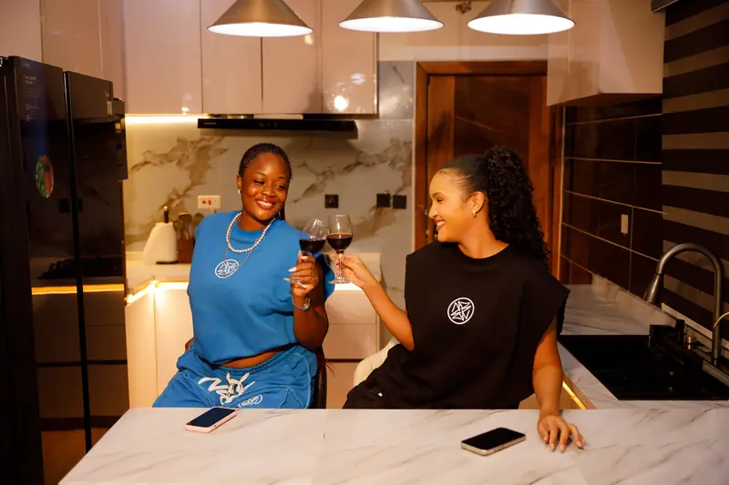 Two women in the Cobalt and Black sets sharing wine in the kitchen