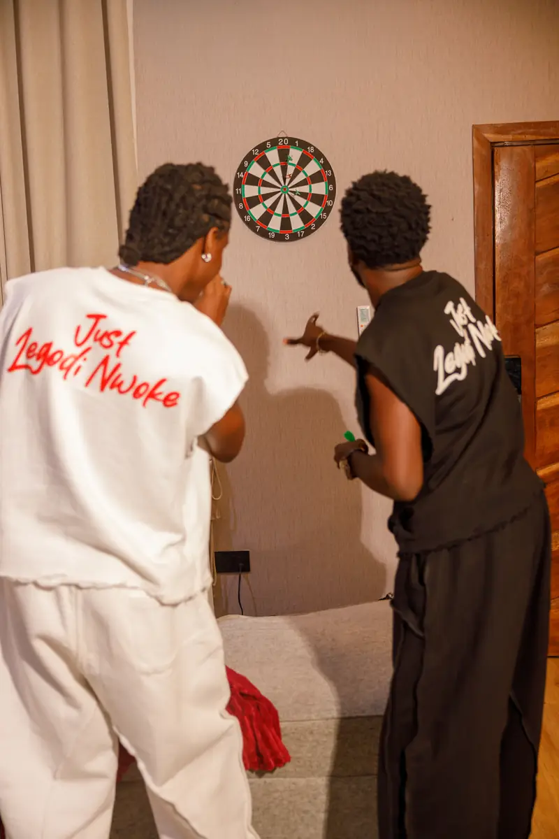 Two men in Bone and Black at the dartboard, back prints showing