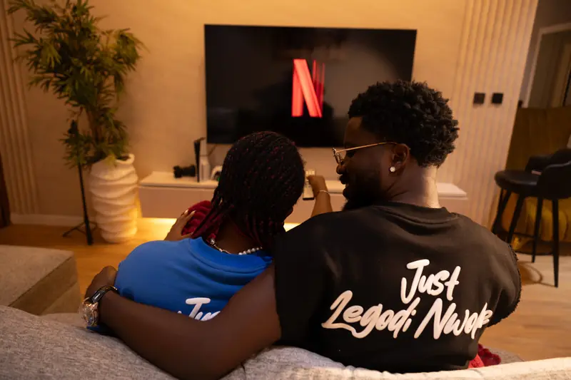 A couple on the sofa watching TV, the Just Legodi Nwoke back print showing